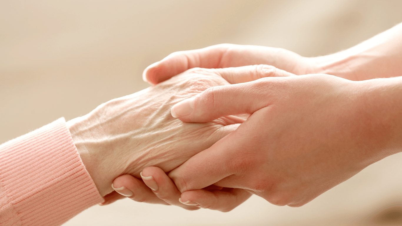 A caregiver holding hands of a senior with dementia
